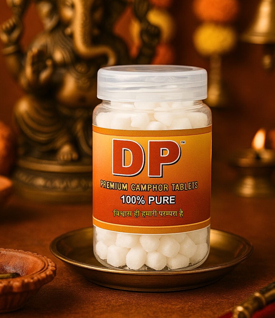 Jar of DP premium camphor tablets (100 g) on a brass plate, set against a warm, worship-themed background with a statue.